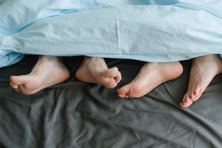Close-up of feet peeking from under a blanket in a cozy setting.
