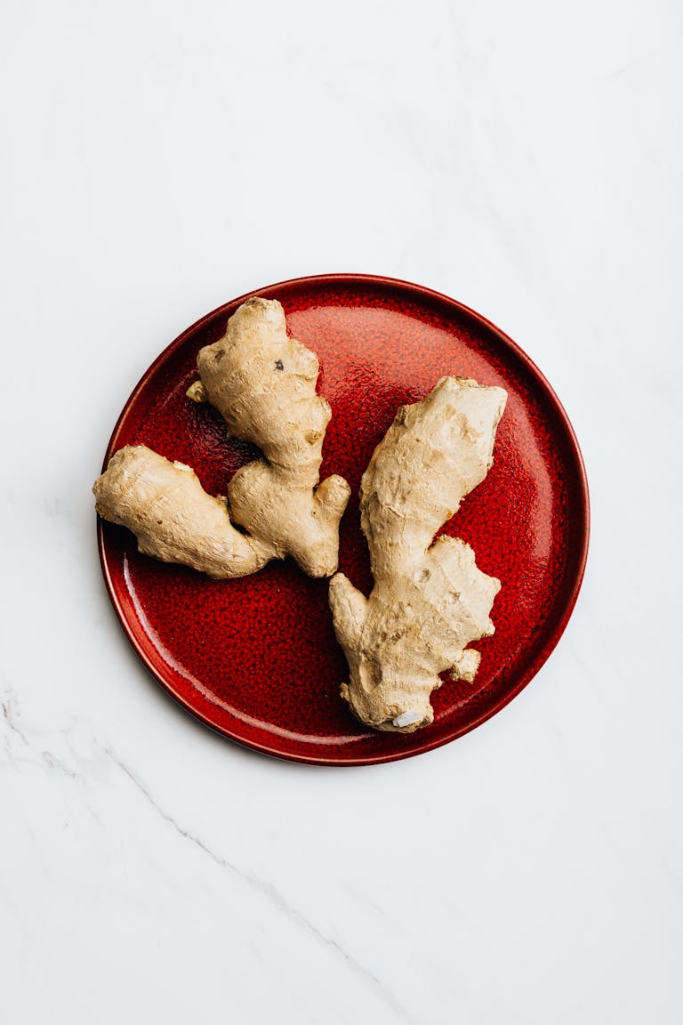 Fresh ginger root on a vibrant red plate, perfect for healthy culinary use.