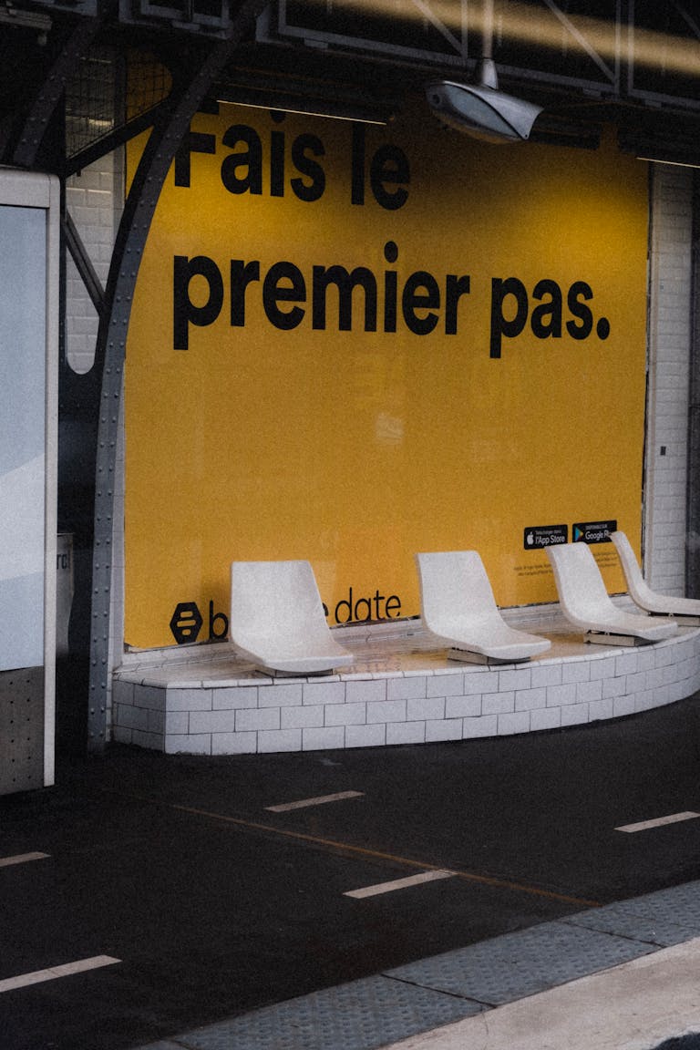 Urban bus station with modern seating and a bold motivational advertisement on a yellow wall.