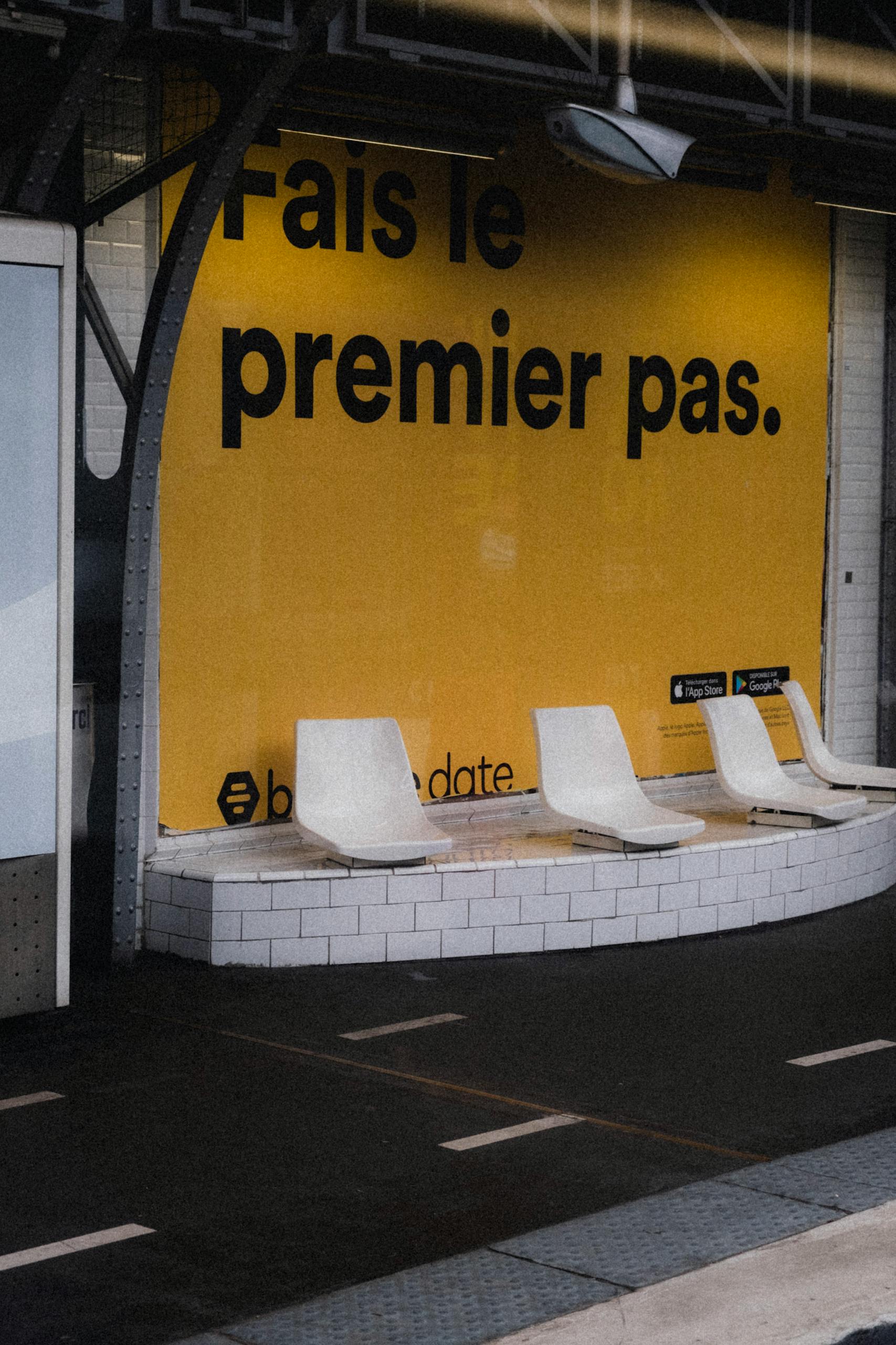 Urban bus station with modern seating and a bold motivational advertisement on a yellow wall.