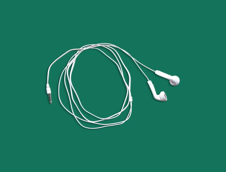 White earphones neatly displayed on a solid green background in a flat lay style.