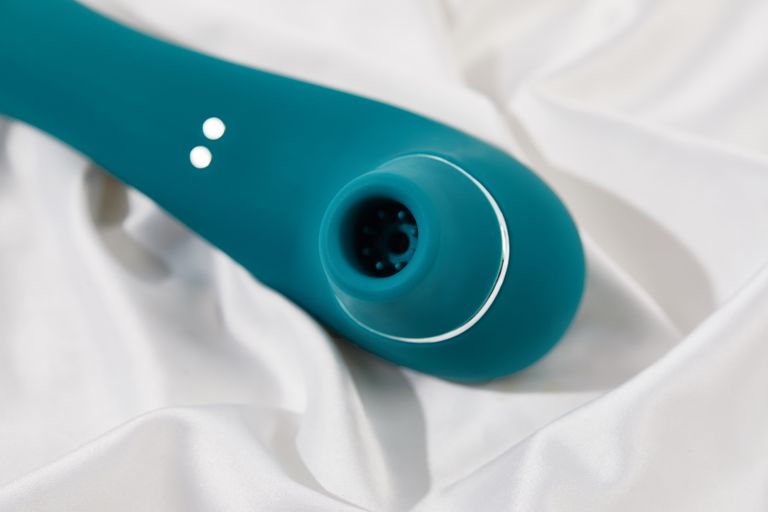 Close-up of a blue silicone device laid on smooth white fabric, highlighting texture and form.