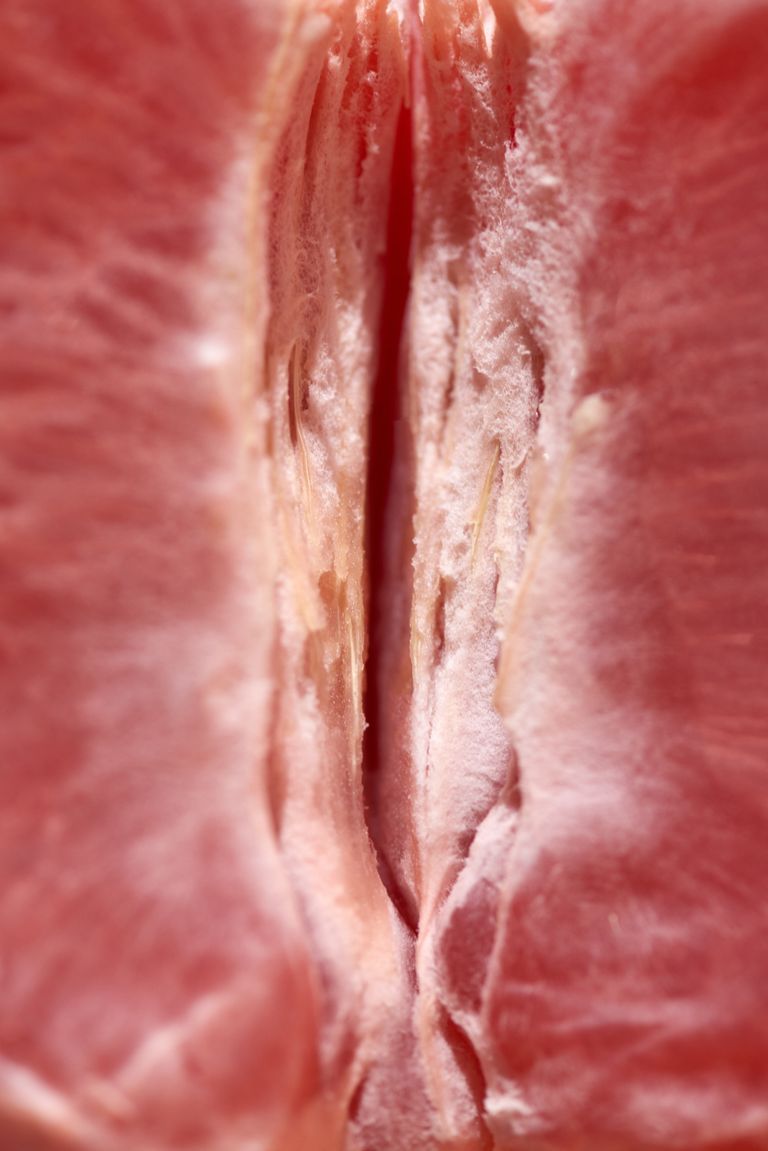 Detailed close-up of a freshly peeled grapefruit section in vertical format.